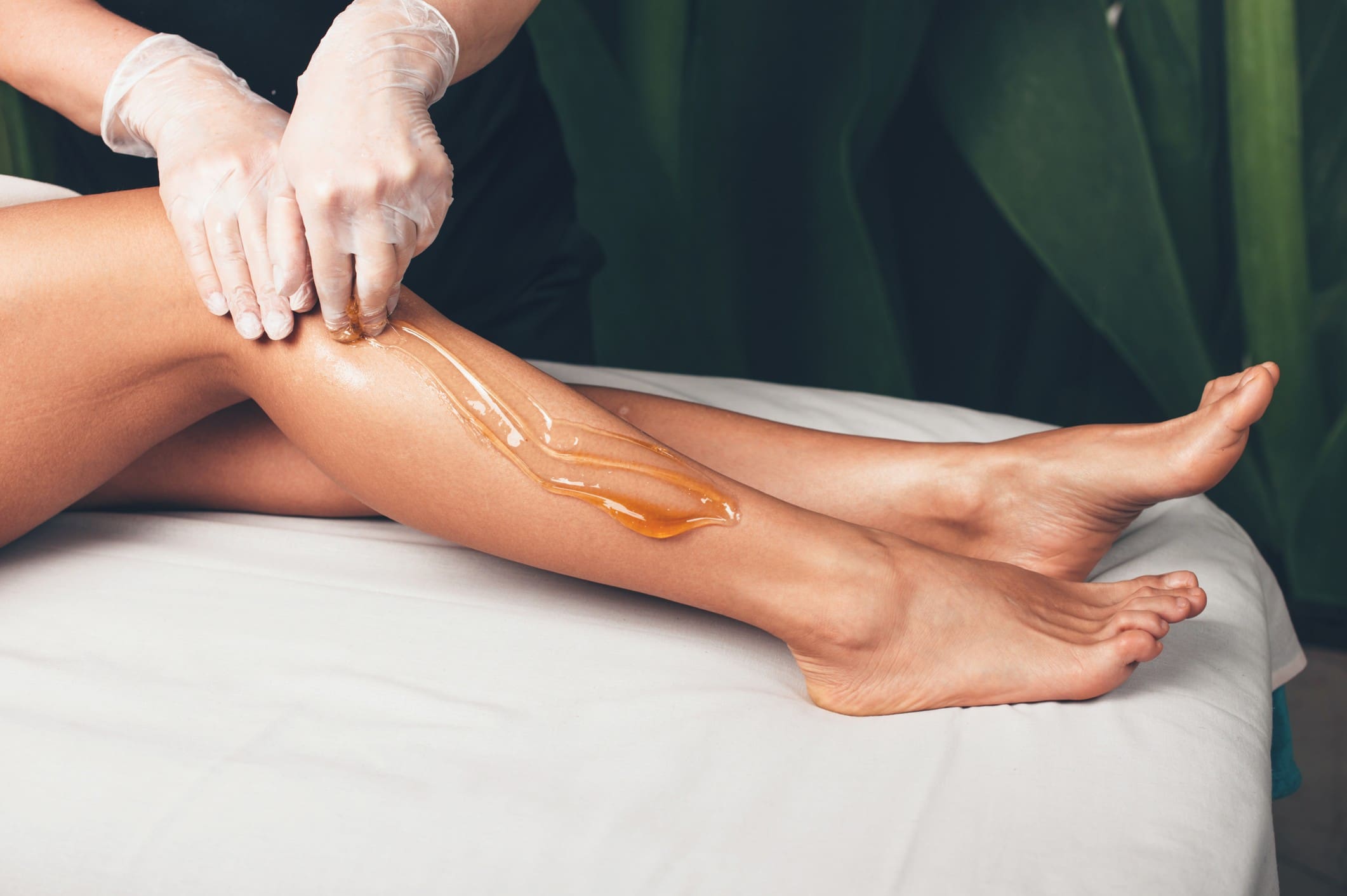 Beautician applying wax on leg